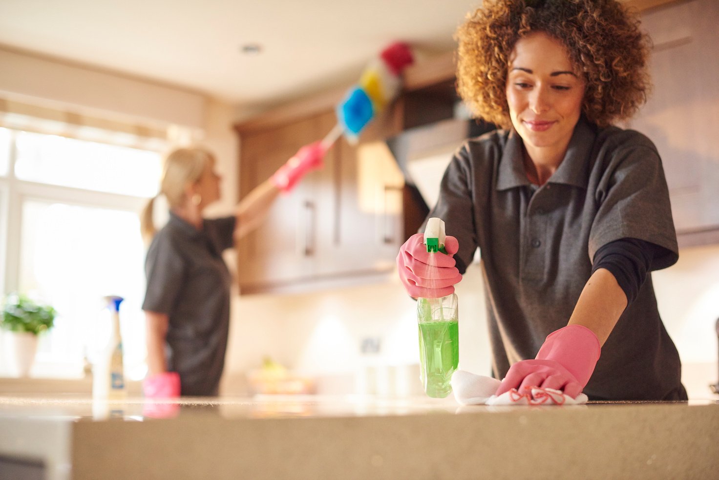 two professional cleaners in a domestic kitchen